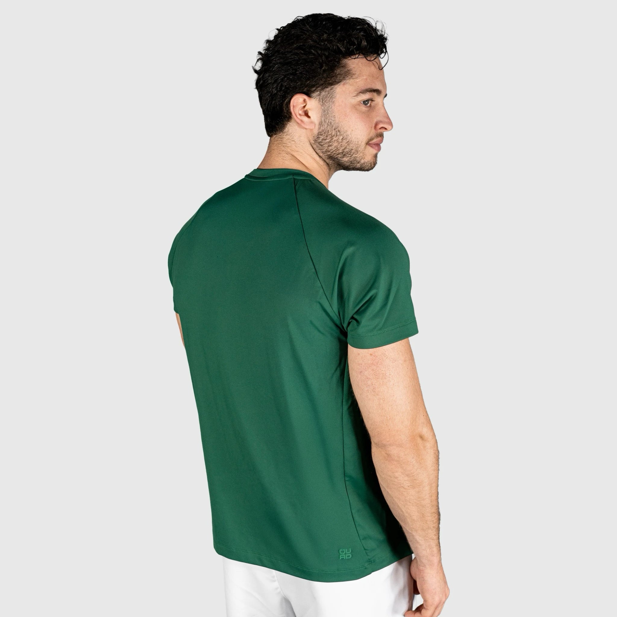 Man wearing a QUAD Ace Padel green T-shirt on a light grey background