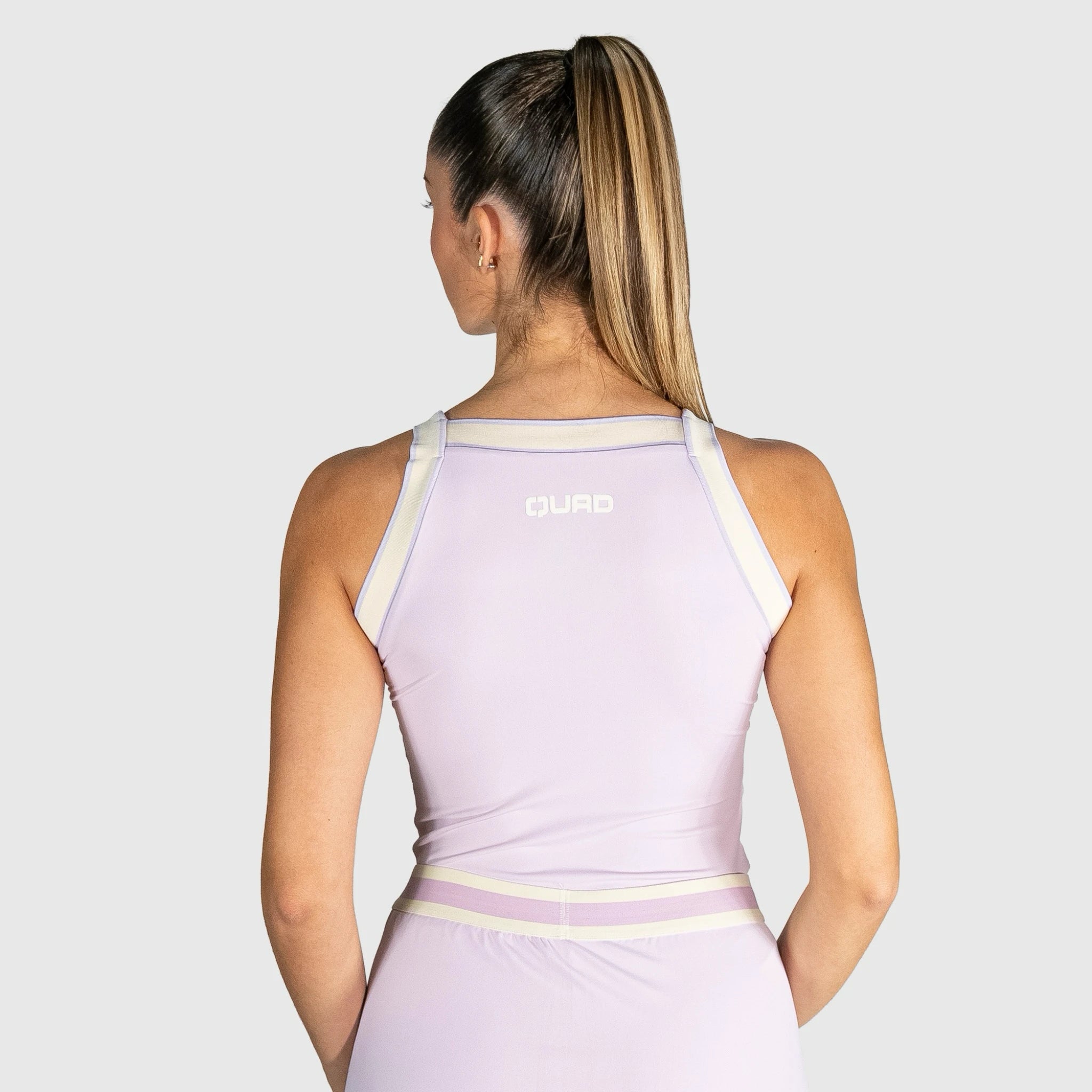 QUAD Aim Padel Top a light purple athletic dress with white straps on a plain background