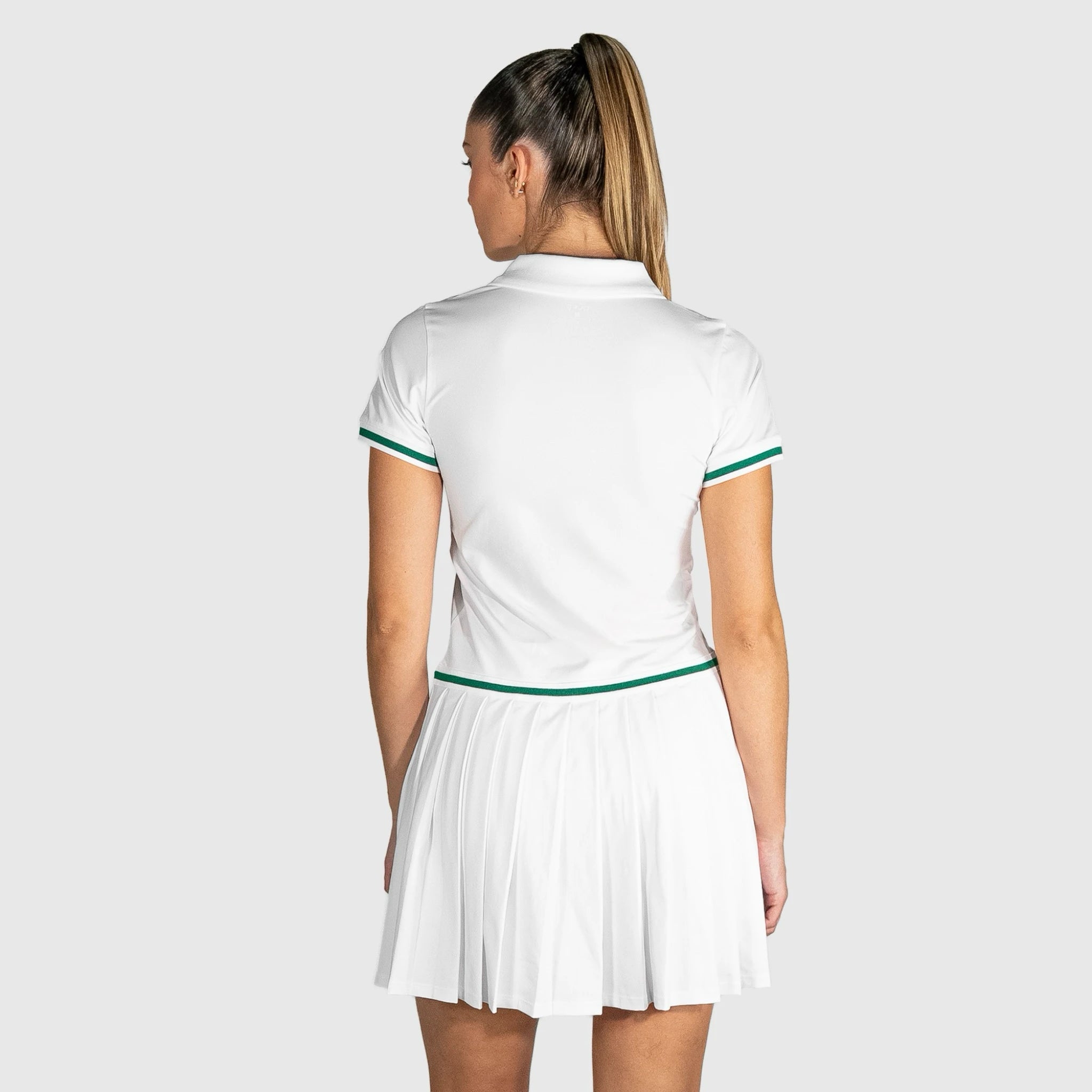 Woman wearing a QUAD Court Padel Dress with green accents on a light gray background
