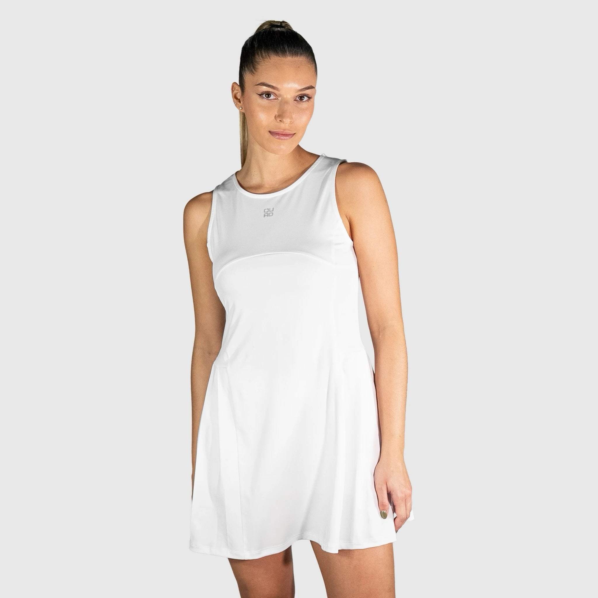 Woman wearing a white QUAD Frame Padel Dress on a light gray background