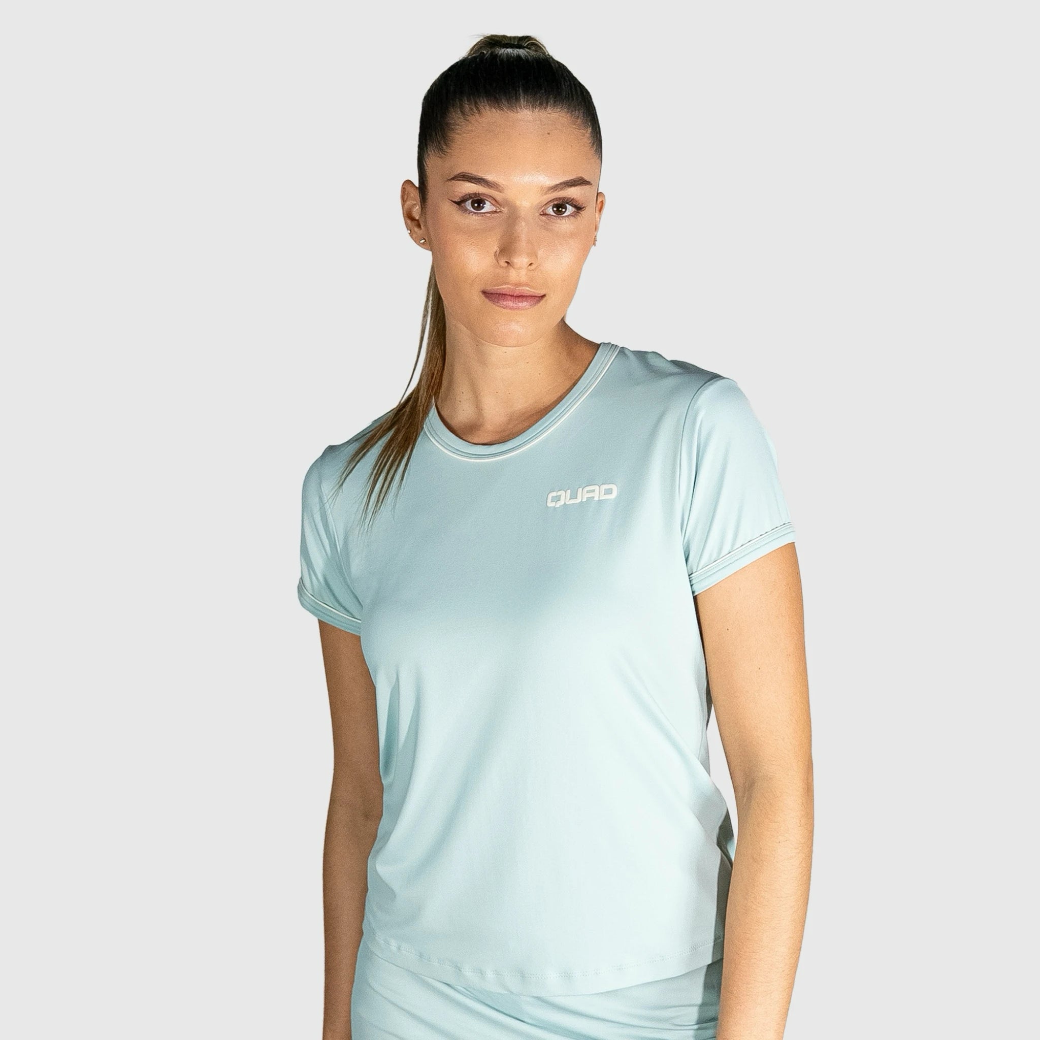 Woman wearing a New Regular Padel shirt with a brand logo on a grey background
