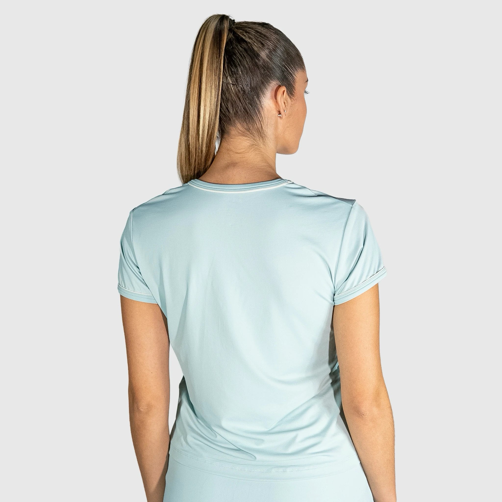 Woman wearing a New Regular Padel shirt outfit on a plain background