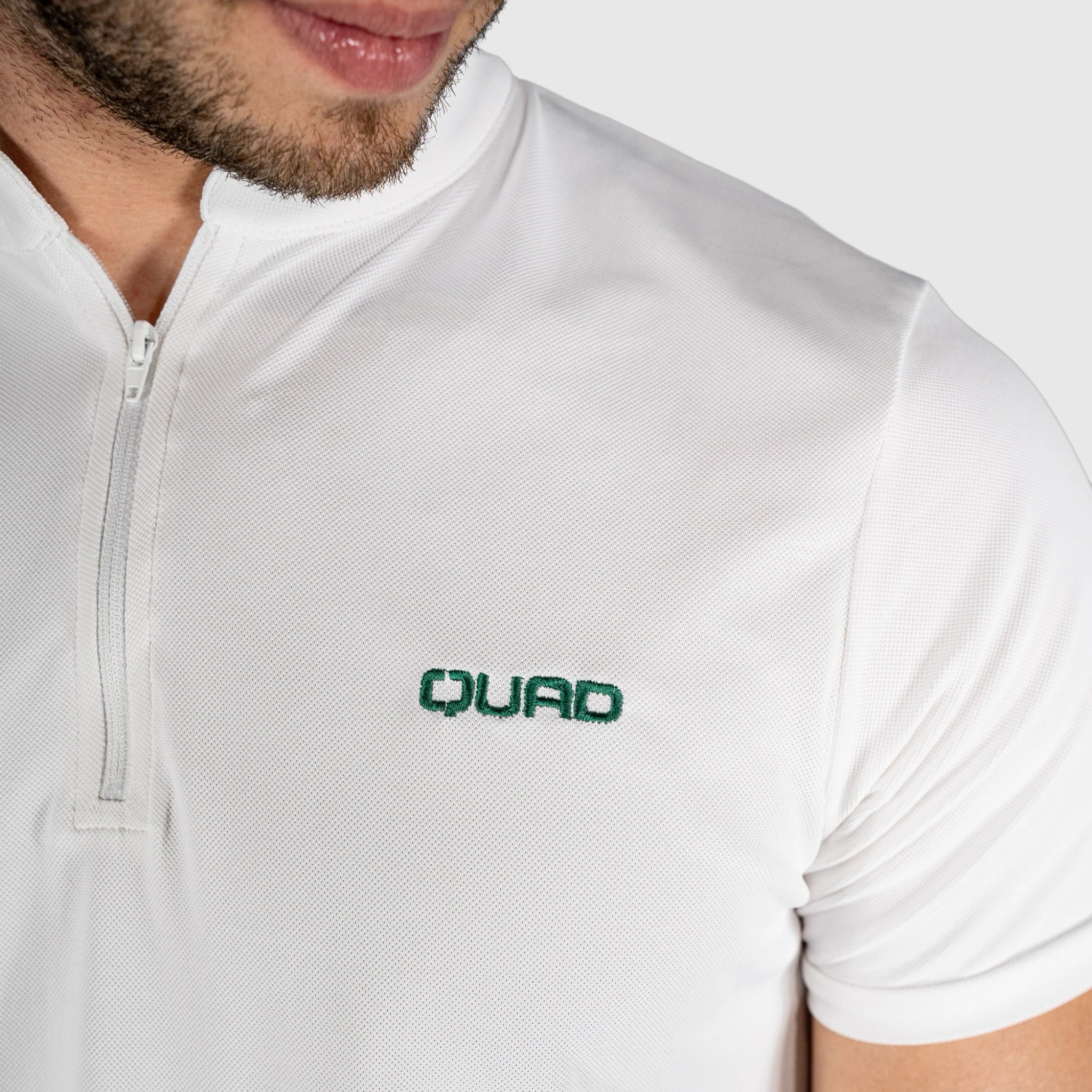 Close-up of a person wearing QUAD Padel Polo White with a neutral background