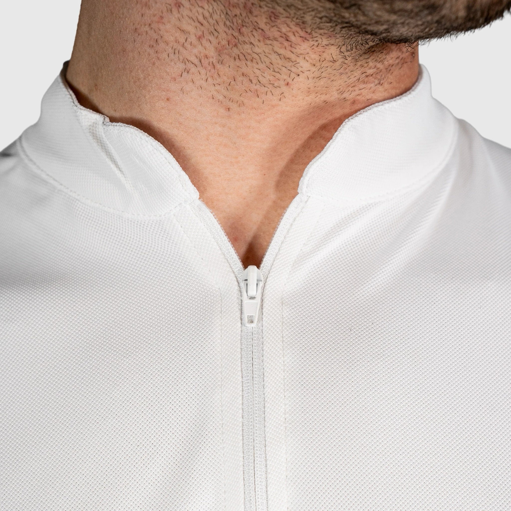 Close-up of a QUAD Padel Polo White with 'QUAD' logo on the collar against a light grey background