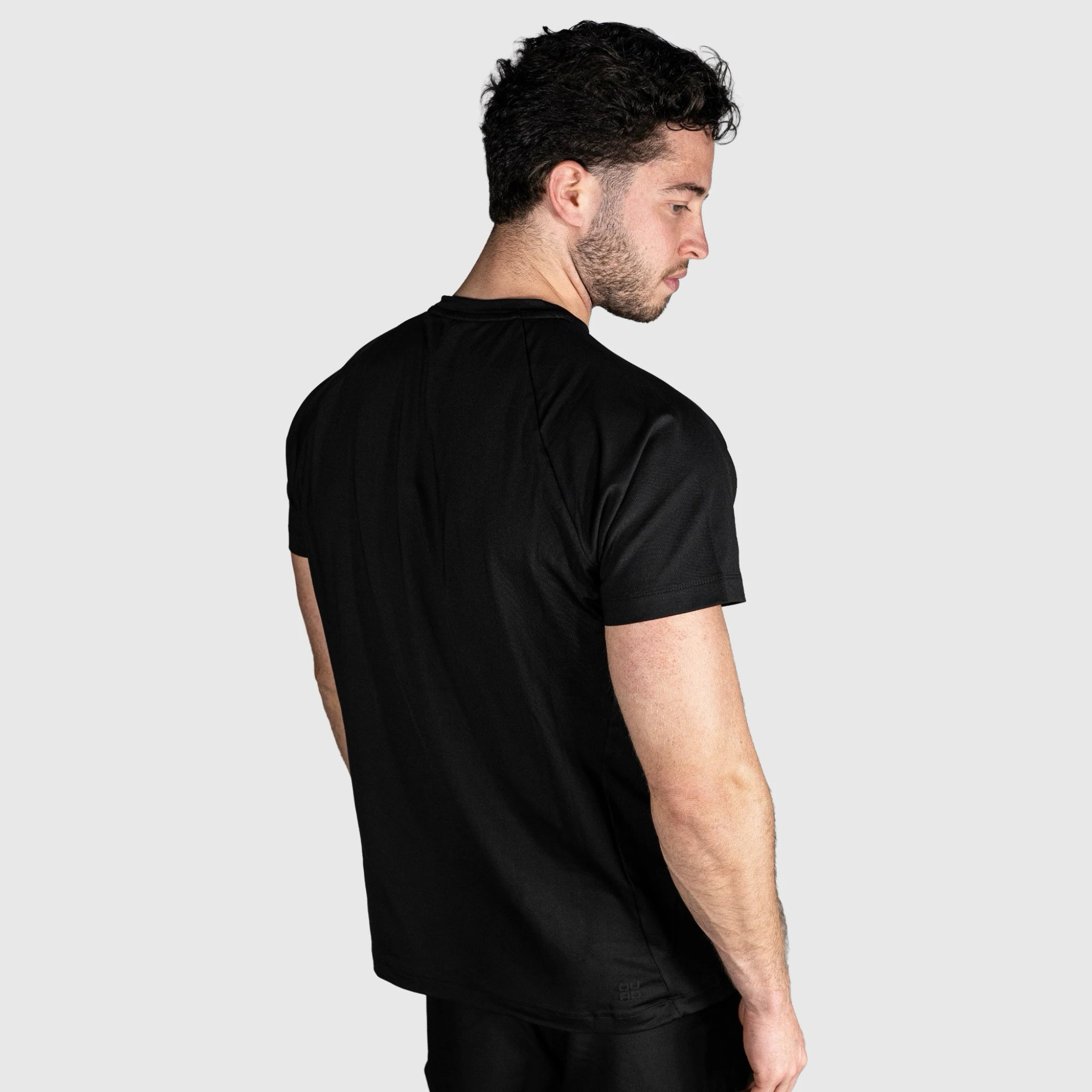 Man wearing a QUAD Ace Padel T shirt  against a light grey background