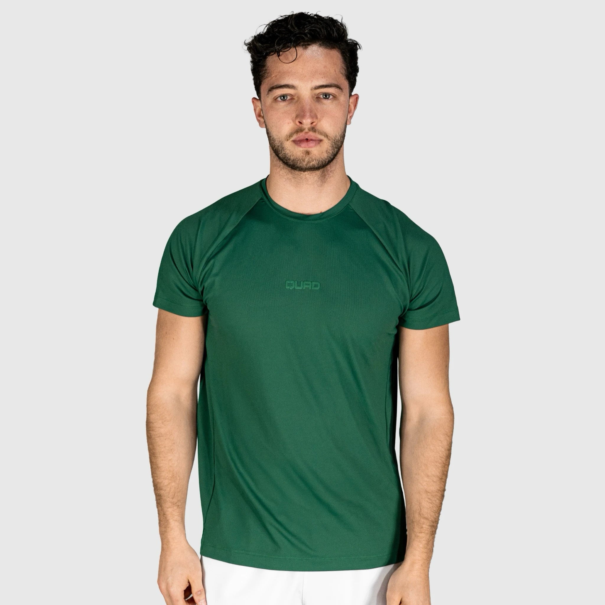 Man wearing a QUAD Ace Padel green T-shirt  with a brand logo on a light grey background