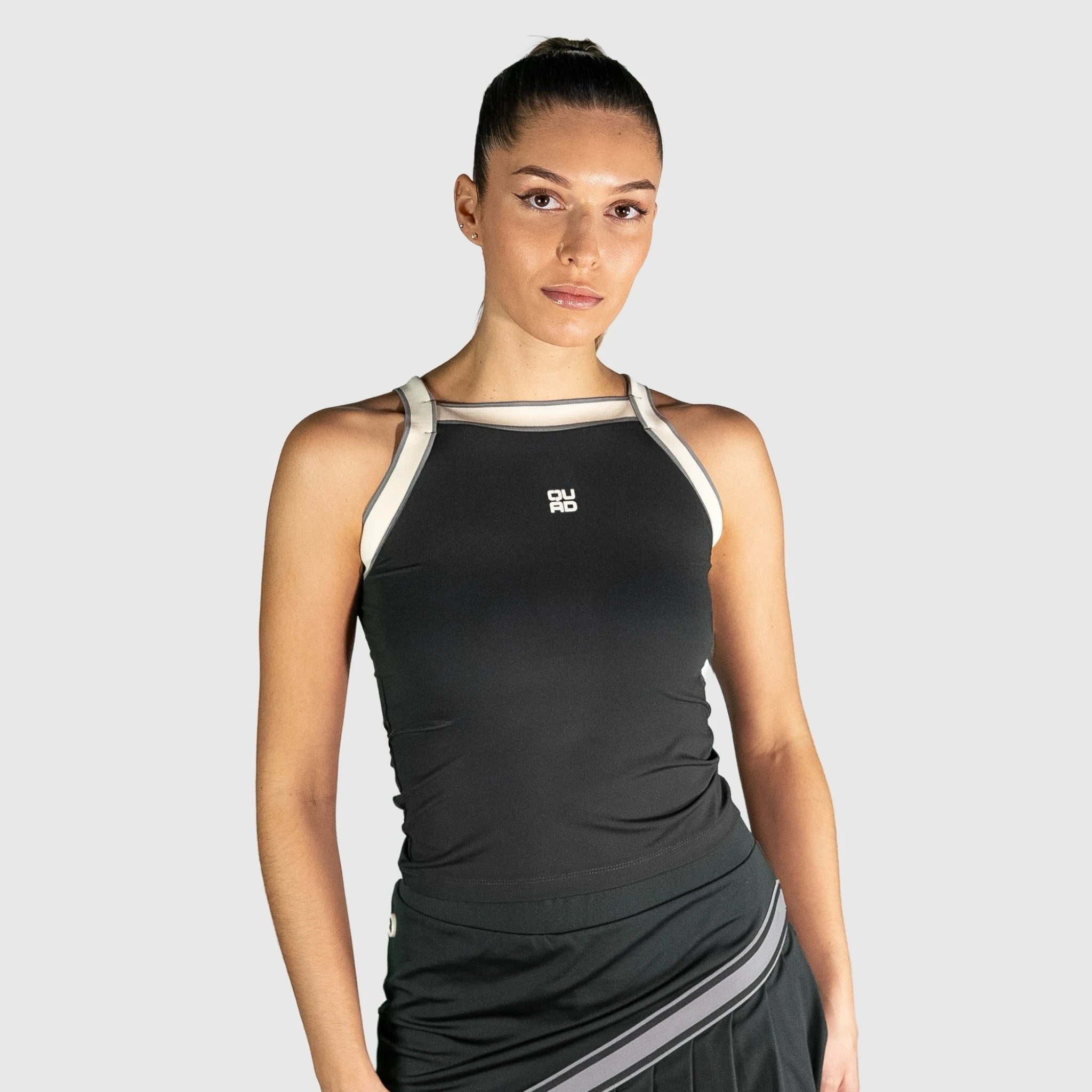 Woman wearing a QUAD Aim Padel Top outfit with a logo on a light grey background