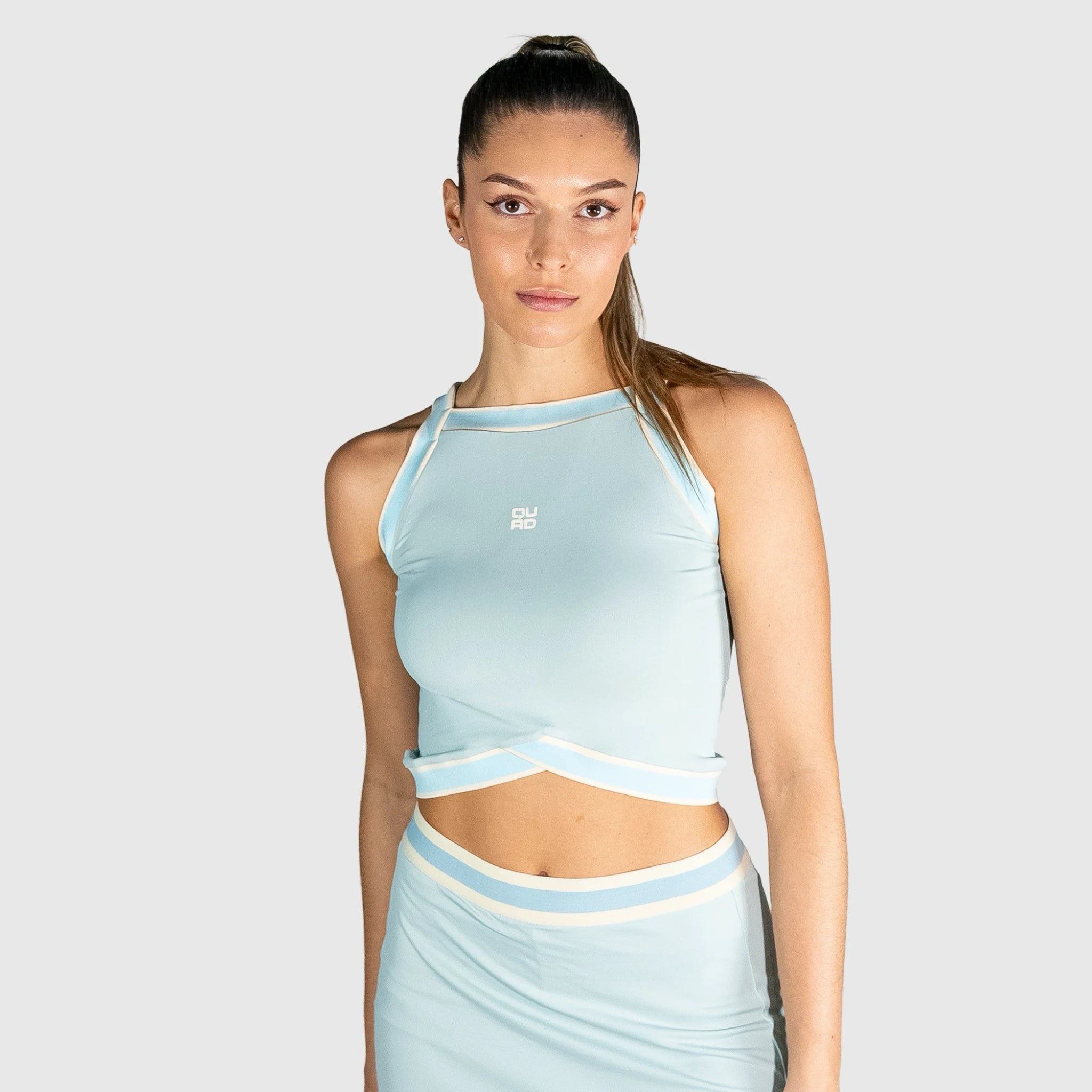 Woman wearing a slice padel top on a plain background