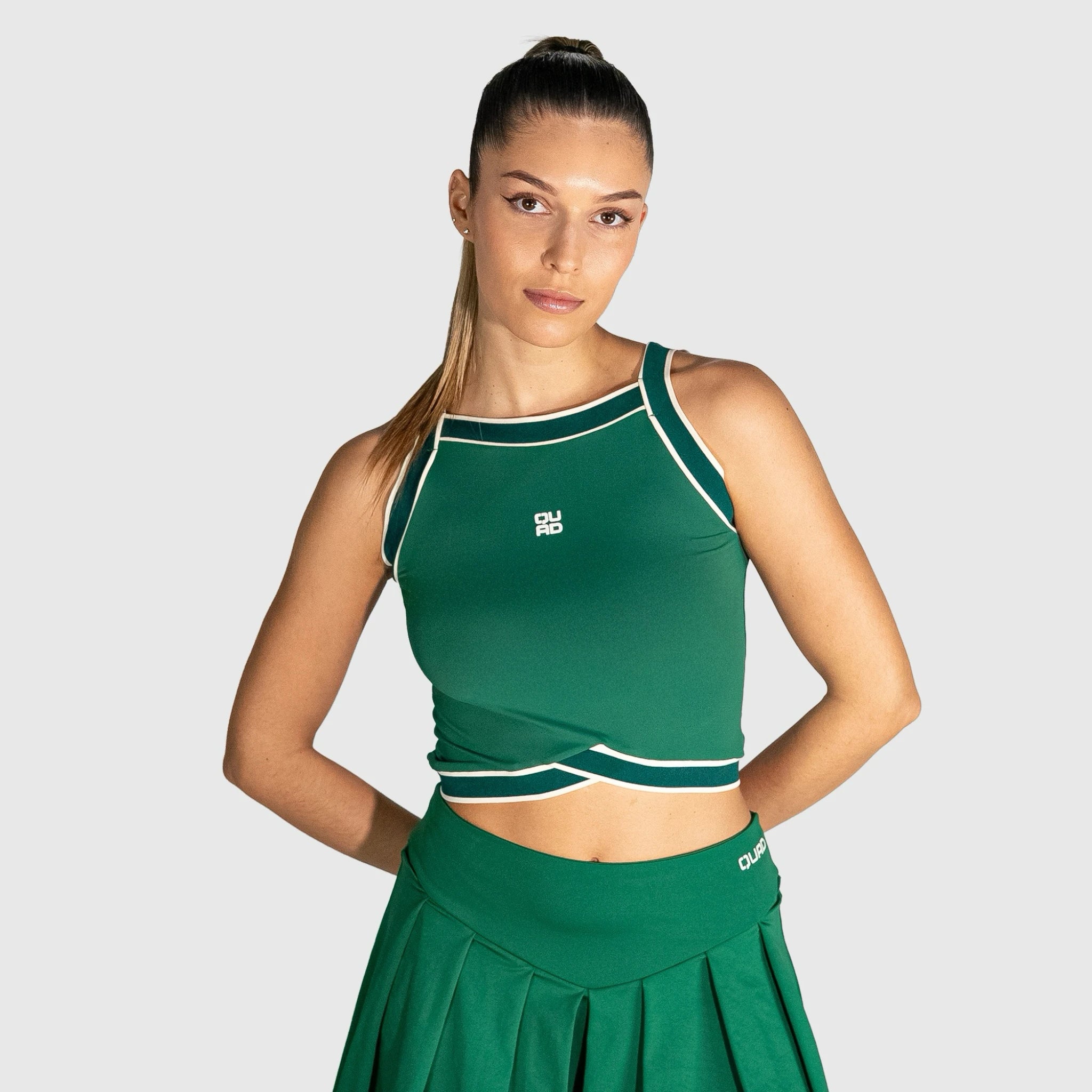 Woman wearing a slice padel top with a logo on a light grey background